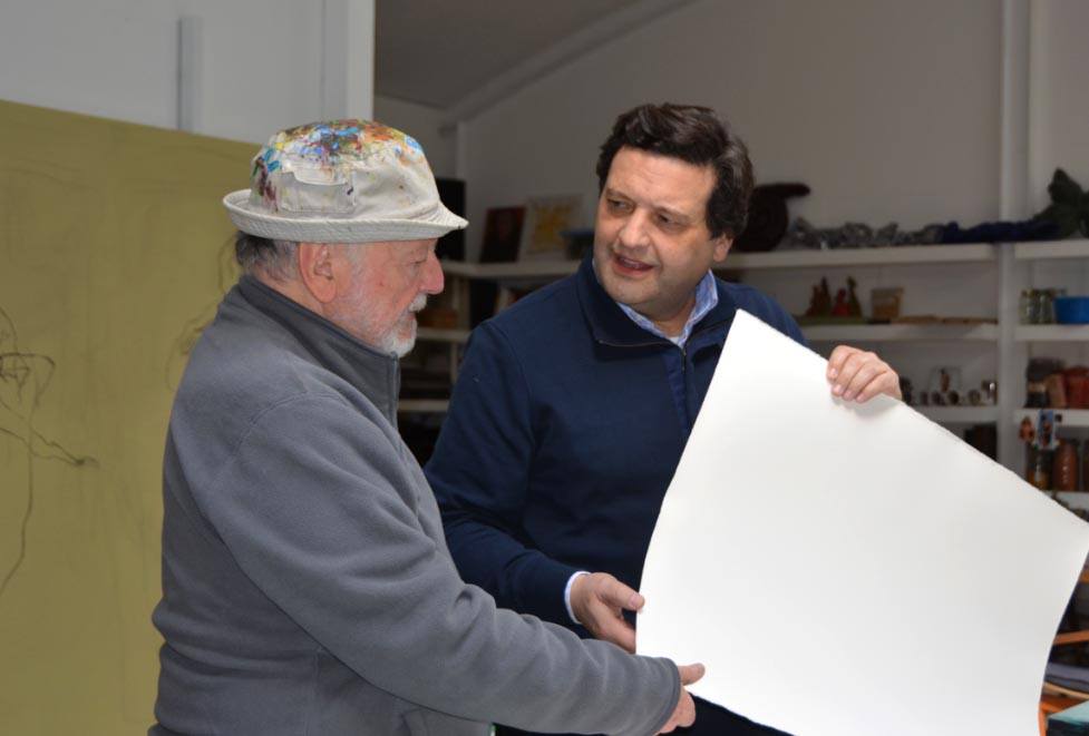Miguel De Lanu artista conversando con el maestro ceramista Martínez Bonatti, observando una pieza de arte en su taller.