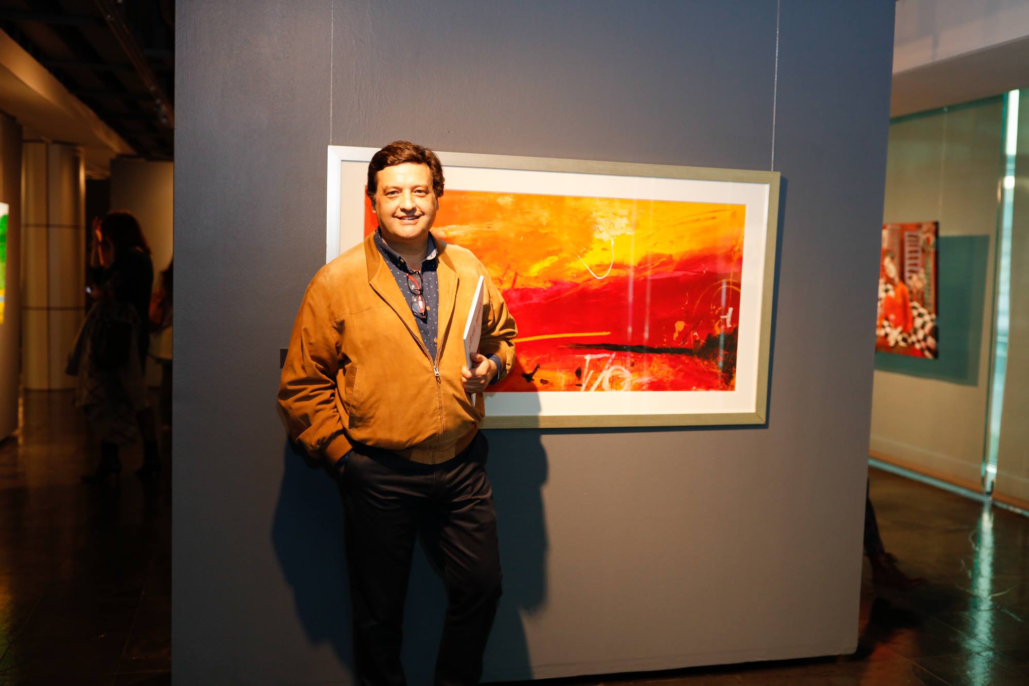 Miguel de Lanú artista chileno en exposición en la Municipalidad de Las Condes junto a una de sus obras.