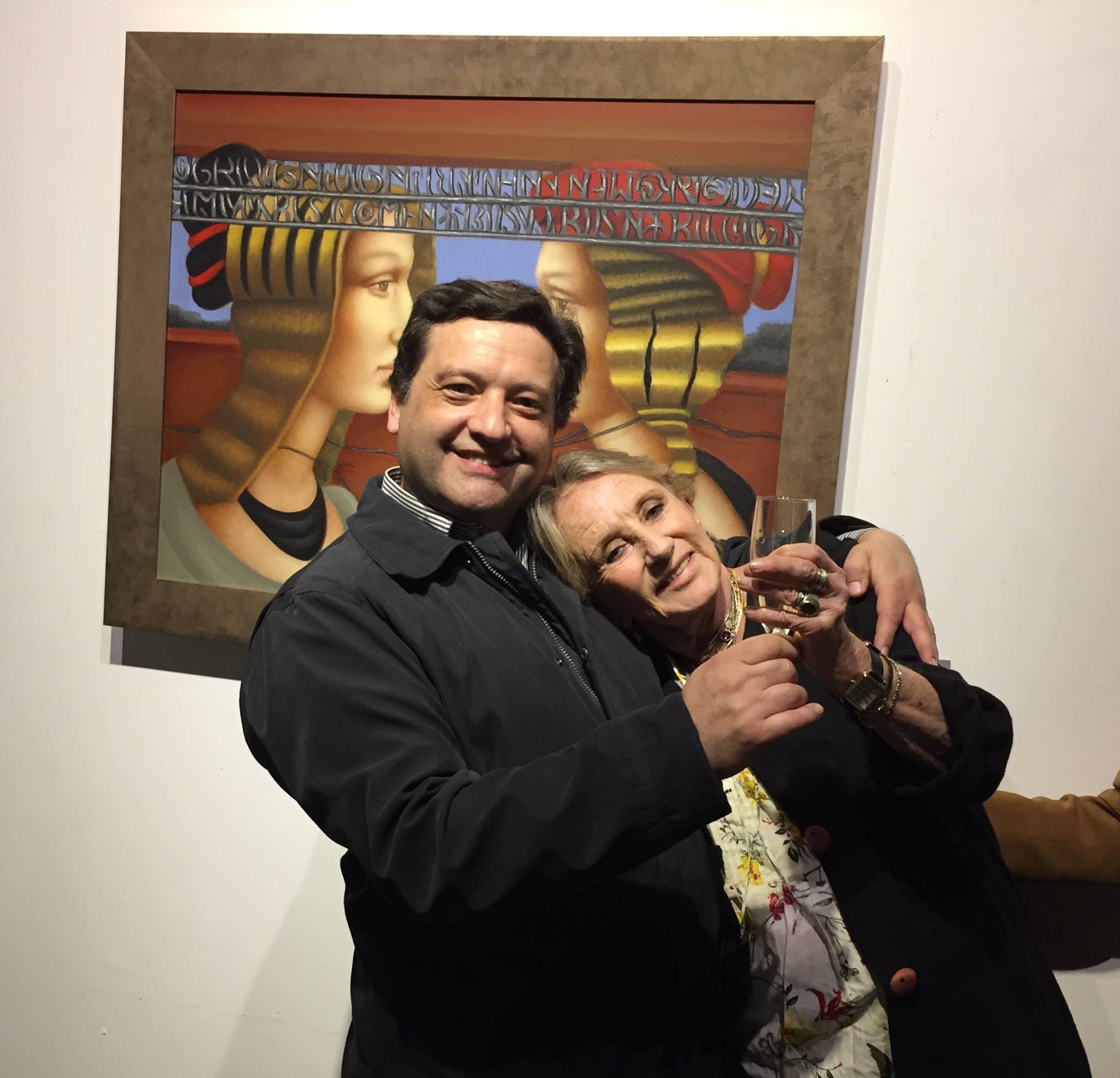 Miguel De Lanu artista y la reconocida pintora Carmen Aldunate brindan en un evento de arte frente a una pintura.